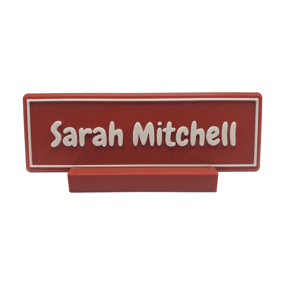 Example personalisation: Small red desk name plate and foot with white raised lettering and border reading Sarah Mitchell