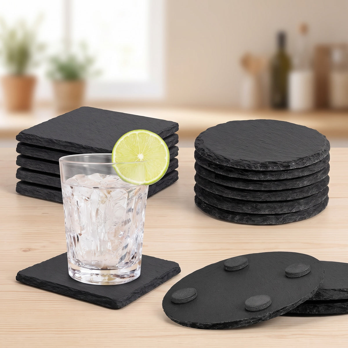 Square and round natural slate stone coasters stacked side by side, one holding a glass of iced water and one flipped to show its rubber feet