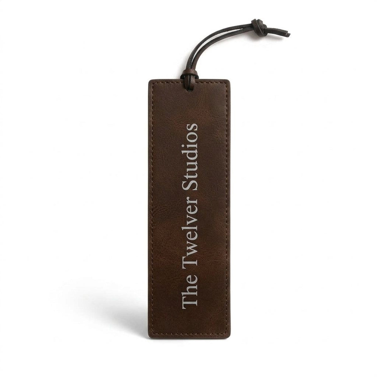 Brown PU leather bookmark with cord tie, engraved in silver with The Twelver Studios, on white